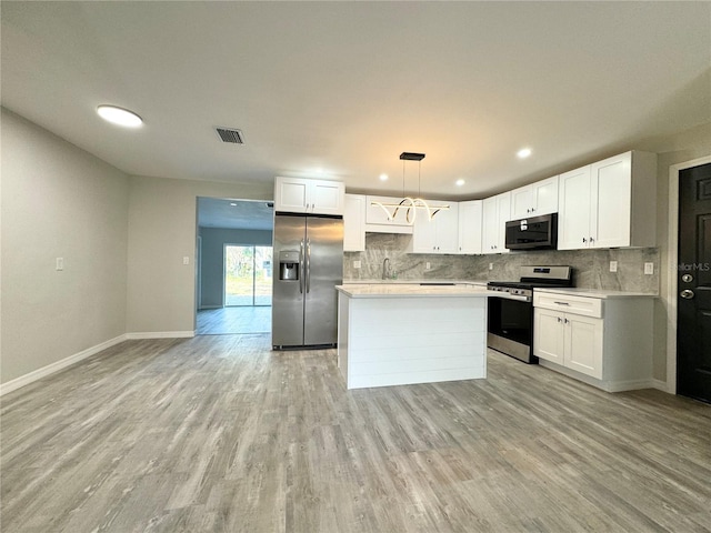 kitchen featuring visible vents, light wood-type flooring, stainless steel appliances, light countertops, and tasteful backsplash