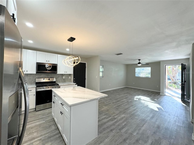 kitchen featuring a center island, backsplash, light wood finished floors, and stainless steel appliances