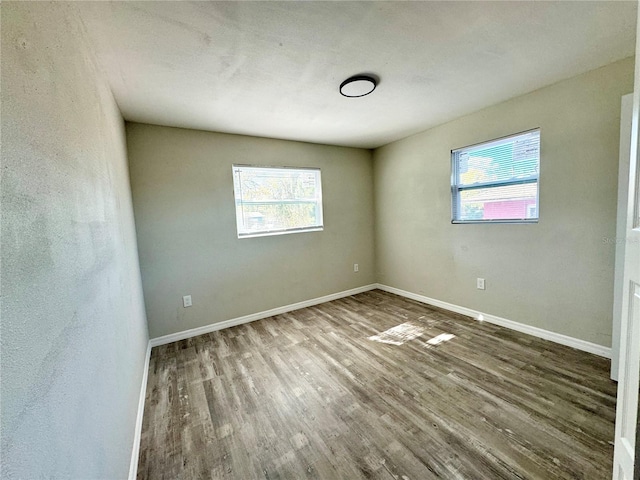 unfurnished room featuring wood finished floors, baseboards, and a wealth of natural light