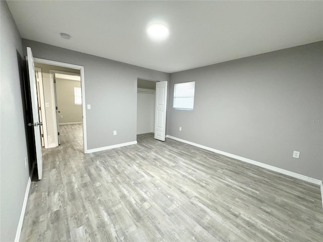 unfurnished bedroom with a closet, light wood-type flooring, and baseboards