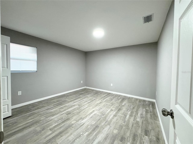 spare room featuring wood finished floors, visible vents, and baseboards