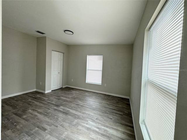 unfurnished bedroom with a closet, visible vents, baseboards, and wood finished floors