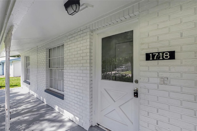 view of exterior entry featuring brick siding