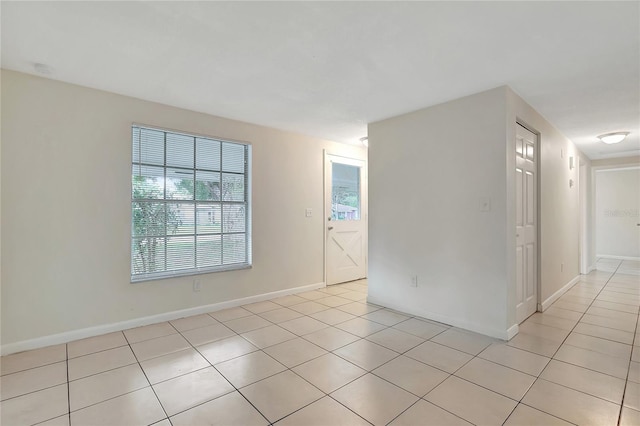 empty room featuring light tile patterned flooring and baseboards