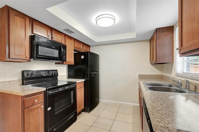 kitchen with light tile patterned floors, a raised ceiling, a sink, black appliances, and baseboards