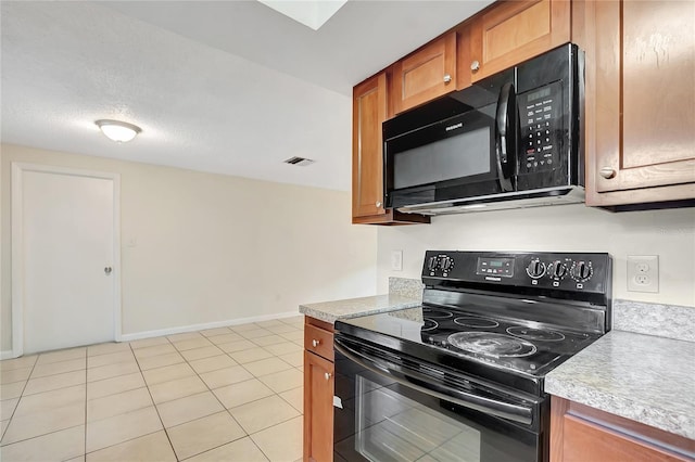 kitchen featuring light tile patterned floors, visible vents, brown cabinets, light countertops, and black appliances