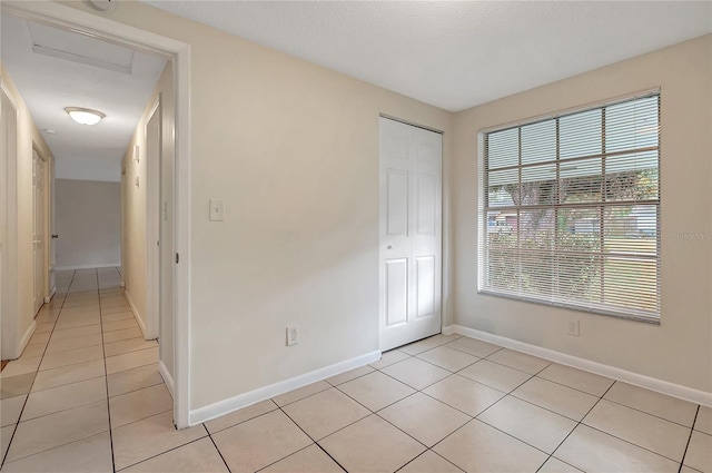 unfurnished room with light tile patterned floors and baseboards