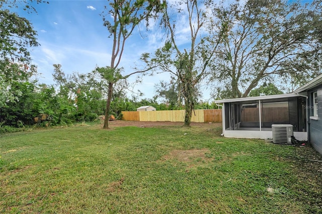 view of yard with fence, a sunroom, and central air condition unit