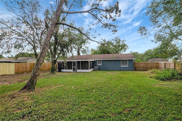 rear view of house with central AC unit, a lawn, a fenced backyard, and a sunroom