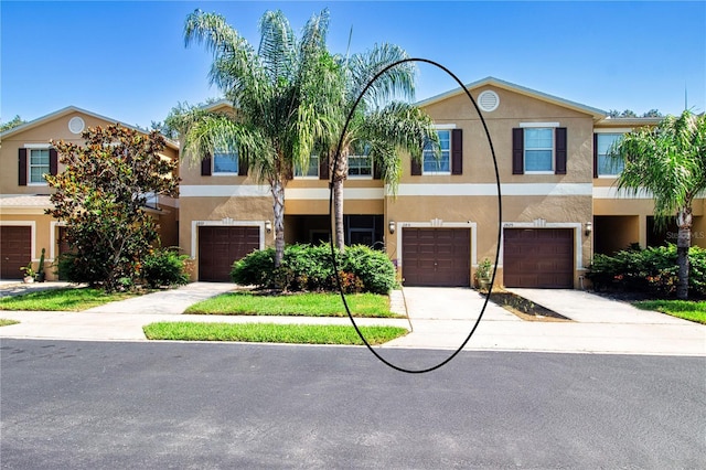 view of property featuring a garage, driveway, and stucco siding