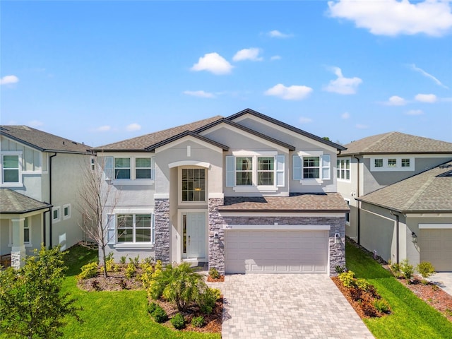 view of front facade with a garage, stone siding, stucco siding, decorative driveway, and a front yard