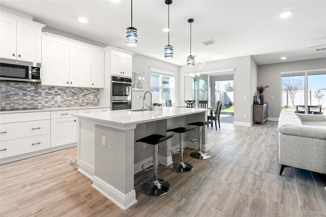 kitchen with stainless steel appliances, visible vents, open floor plan, light countertops, and decorative backsplash