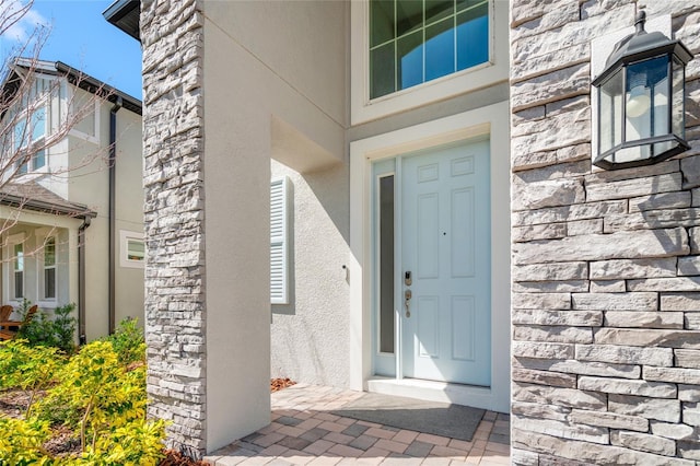 property entrance featuring stone siding and stucco siding