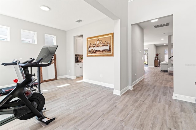 exercise area featuring light wood-style floors, baseboards, and visible vents