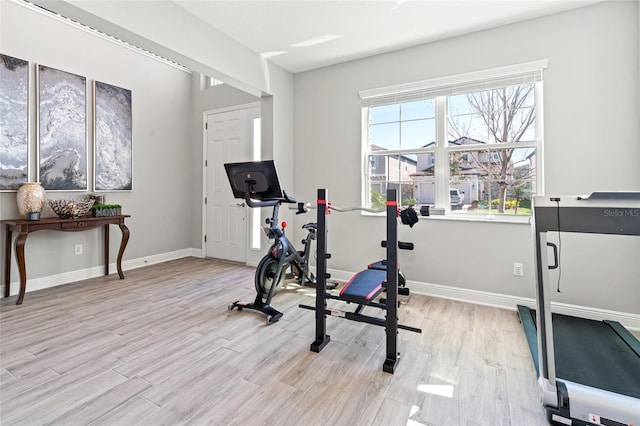 workout room with baseboards and light wood-style floors