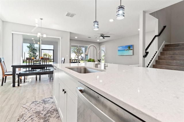 kitchen featuring visible vents, white cabinets, light stone counters, pendant lighting, and a sink