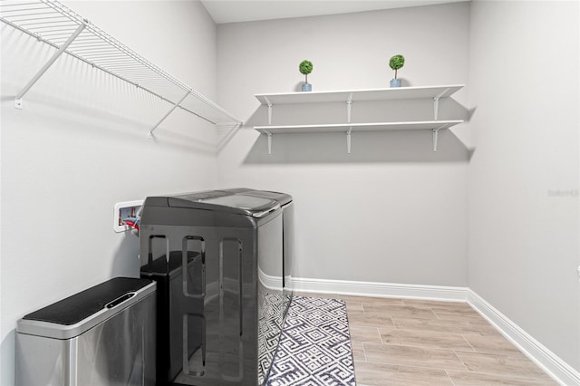 laundry room featuring laundry area, baseboards, washer and clothes dryer, and wood finish floors