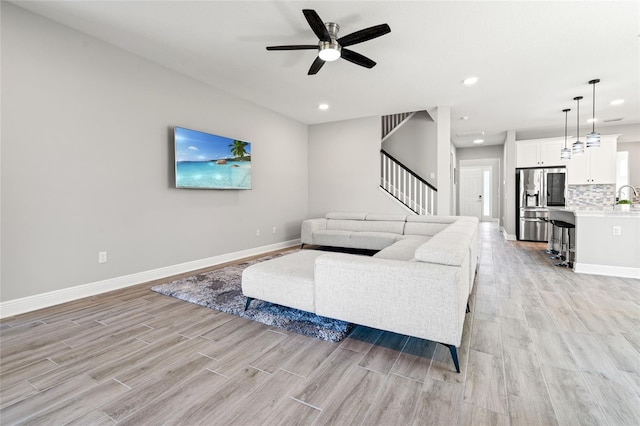 living area featuring light wood finished floors, baseboards, stairway, and recessed lighting