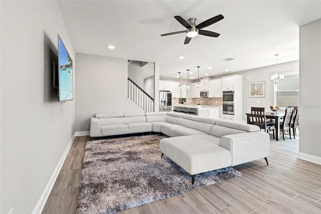 living room featuring light wood-type flooring, visible vents, and baseboards