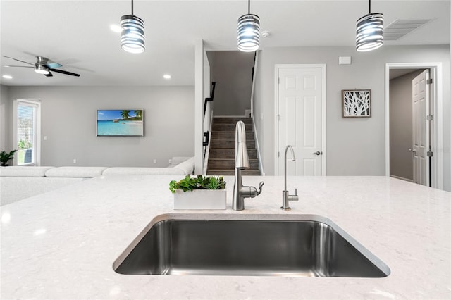 kitchen with visible vents, a ceiling fan, open floor plan, decorative light fixtures, and a sink