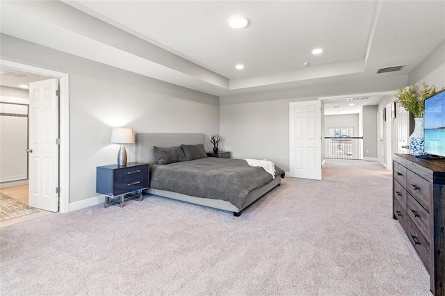 bedroom featuring light carpet, baseboards, visible vents, and a tray ceiling