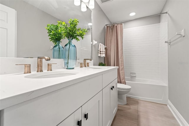 full bath with double vanity, a sink, toilet, and tile patterned floors