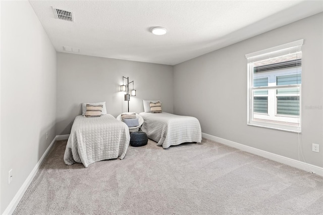 carpeted bedroom featuring visible vents, a textured ceiling, and baseboards