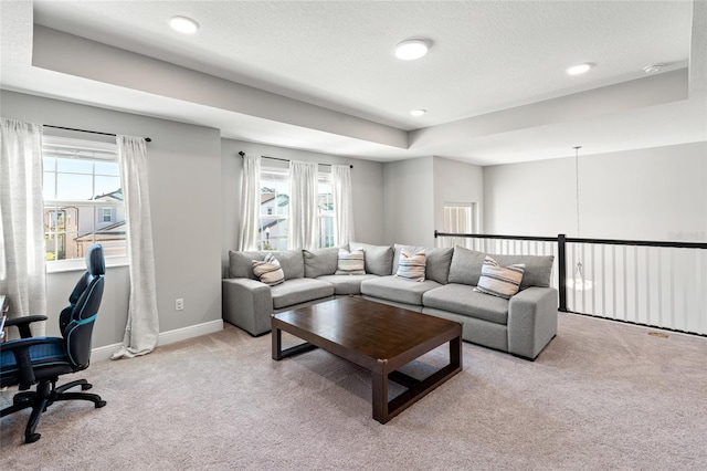 living room with a tray ceiling, plenty of natural light, and light colored carpet