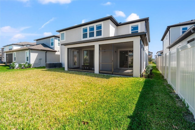 rear view of house featuring central AC unit, a lawn, a sunroom, fence, and stucco siding