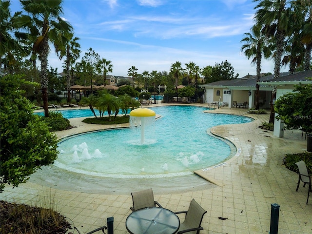 community pool with a patio area and fence