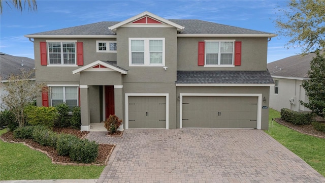 view of front facade featuring a shingled roof, decorative driveway, and stucco siding