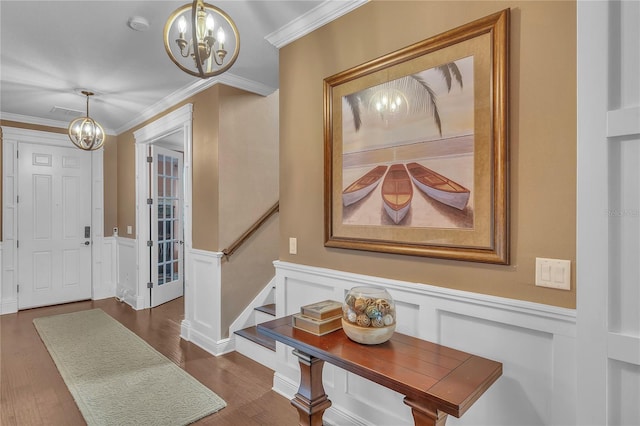 entryway with an inviting chandelier, stairs, crown molding, and wainscoting