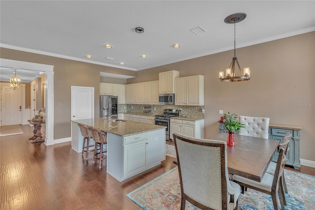 kitchen with visible vents, decorative backsplash, an island with sink, stainless steel appliances, and a notable chandelier