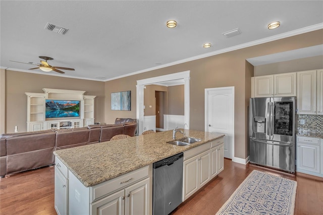 kitchen with light stone counters, stainless steel appliances, wood finished floors, a sink, and visible vents