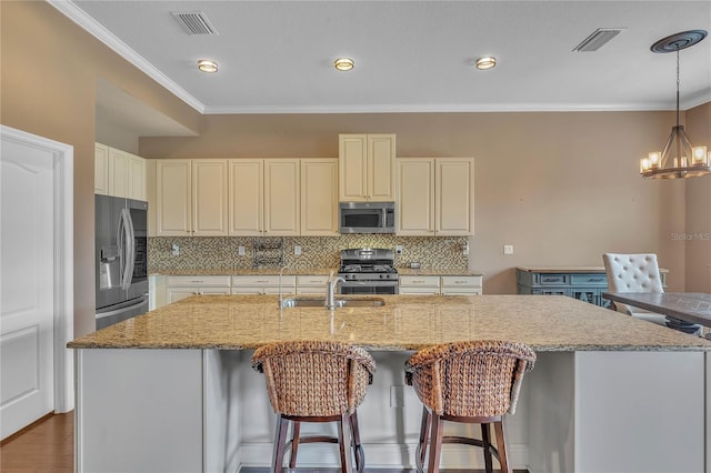 kitchen with a sink, visible vents, ornamental molding, appliances with stainless steel finishes, and backsplash