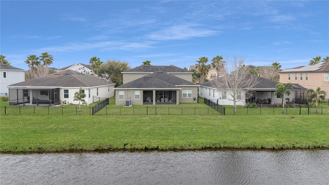 back of house featuring a water view, a sunroom, a fenced backyard, and a lawn