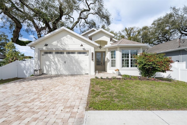 ranch-style house featuring a garage, fence, decorative driveway, stucco siding, and a front lawn