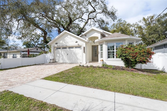 ranch-style house with decorative driveway, stucco siding, fence, a garage, and a front lawn