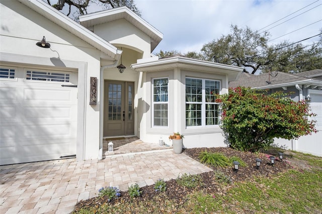 entrance to property with a garage and stucco siding