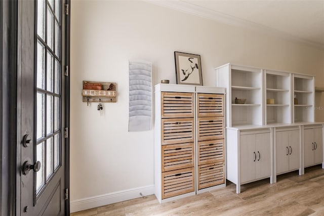 interior space featuring baseboards, ornamental molding, and wood finished floors