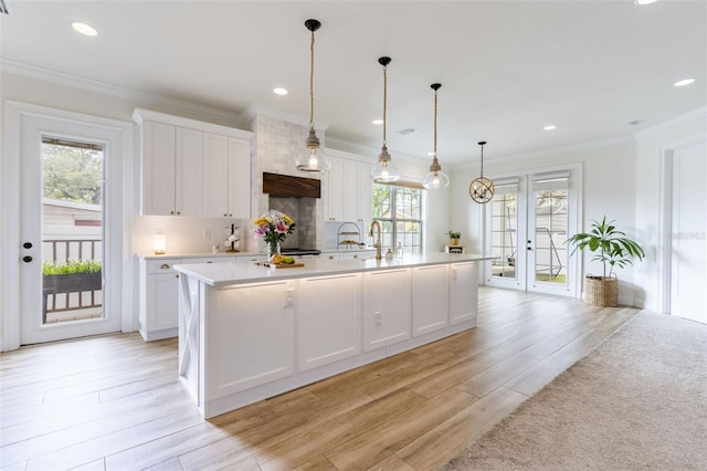 kitchen with light countertops, backsplash, ornamental molding, light wood-style floors, and white cabinets