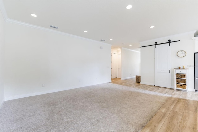 empty room with a barn door, visible vents, crown molding, and recessed lighting