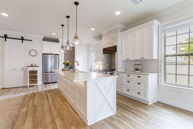 kitchen with crown molding, backsplash, a barn door, a sink, and stainless steel fridge