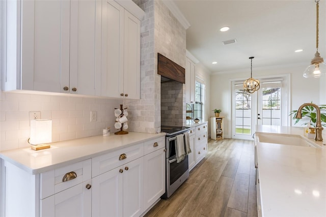 kitchen featuring visible vents, ornamental molding, white cabinetry, a sink, and light wood-type flooring