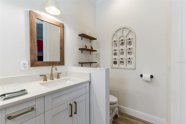 bathroom featuring wood finished floors, vanity, toilet, and baseboards