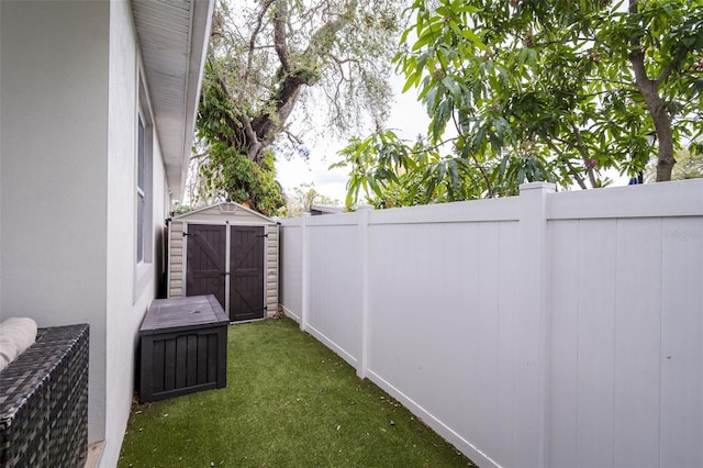 view of yard featuring a fenced backyard, a storage unit, and an outbuilding