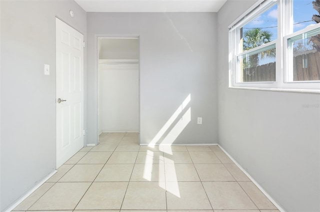 hall featuring baseboards and light tile patterned flooring