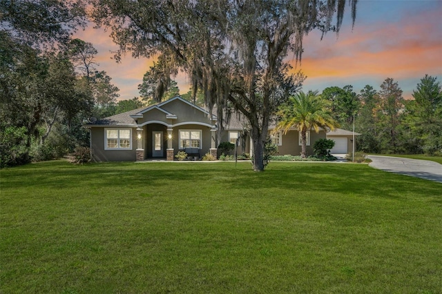 view of front of property featuring a garage, stucco siding, a lawn, and concrete driveway