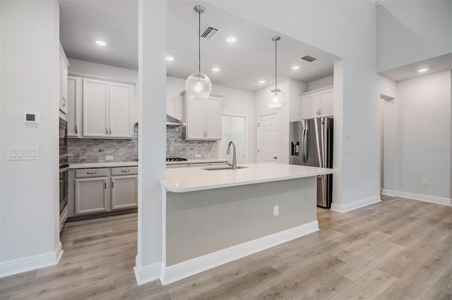 kitchen featuring visible vents, light wood finished floors, a sink, stainless steel appliances, and light countertops