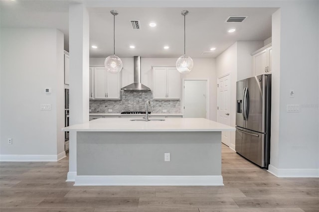 kitchen with visible vents, wall chimney exhaust hood, stainless steel refrigerator with ice dispenser, and a sink